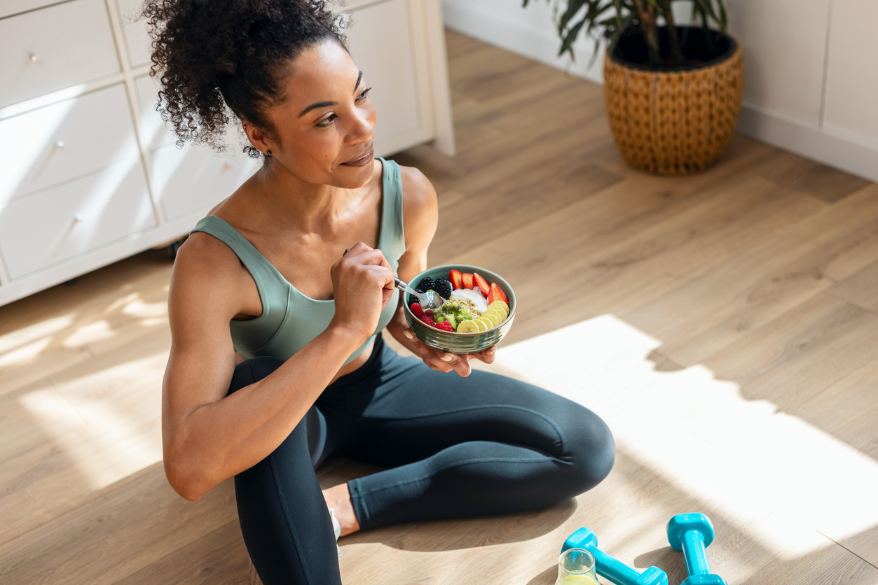 Person in workout attire enjoying a healthy fruit bowl after exercise thanks for smart goal examples.