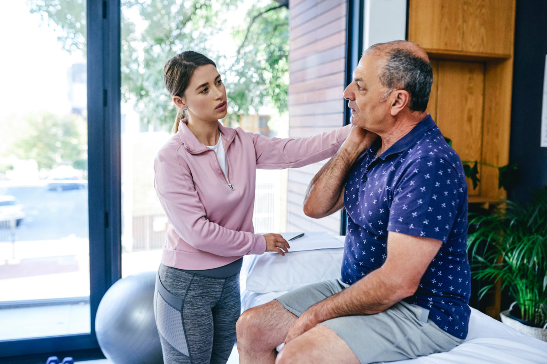 Woman helping a man with neck pain